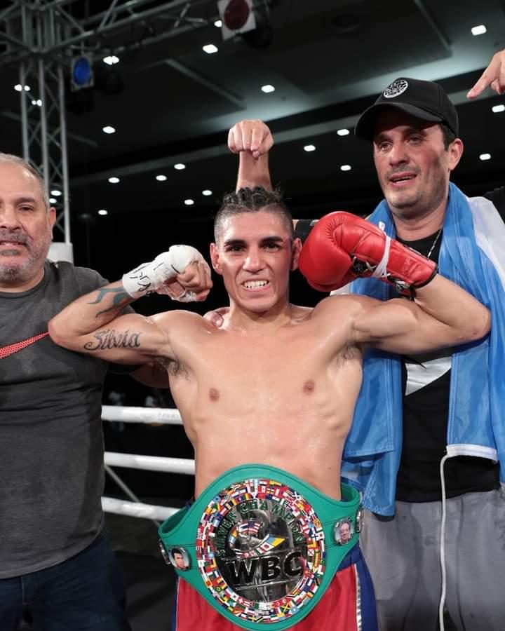 Fernando «Puma» Martínez, con el cinturón del Consejo Mundial de Boxeo, muestra los bíceps sobre el ring; detrás, Calabrese con la bandera argentina sobre los hombros