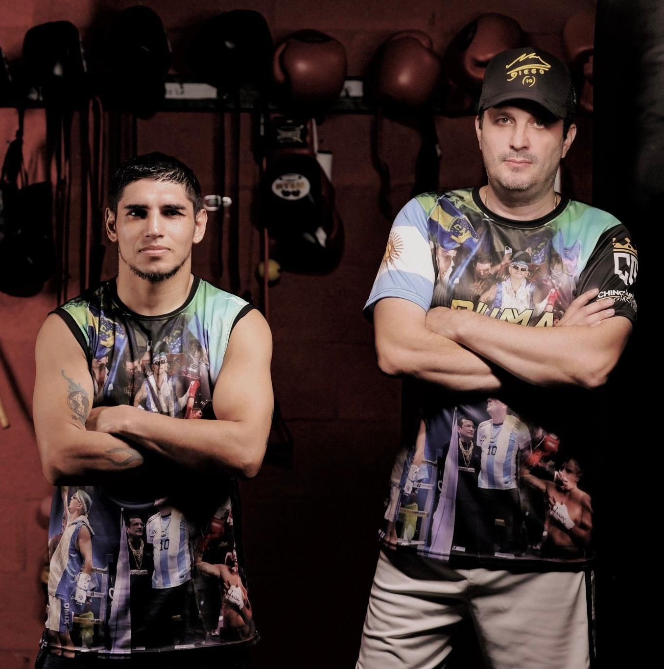 Rodrigo Calabrese, de gorra y con los brazos cruzados, junto a Fernando «Puma» Martínez en un gimnasio con guantes colgados en la pared