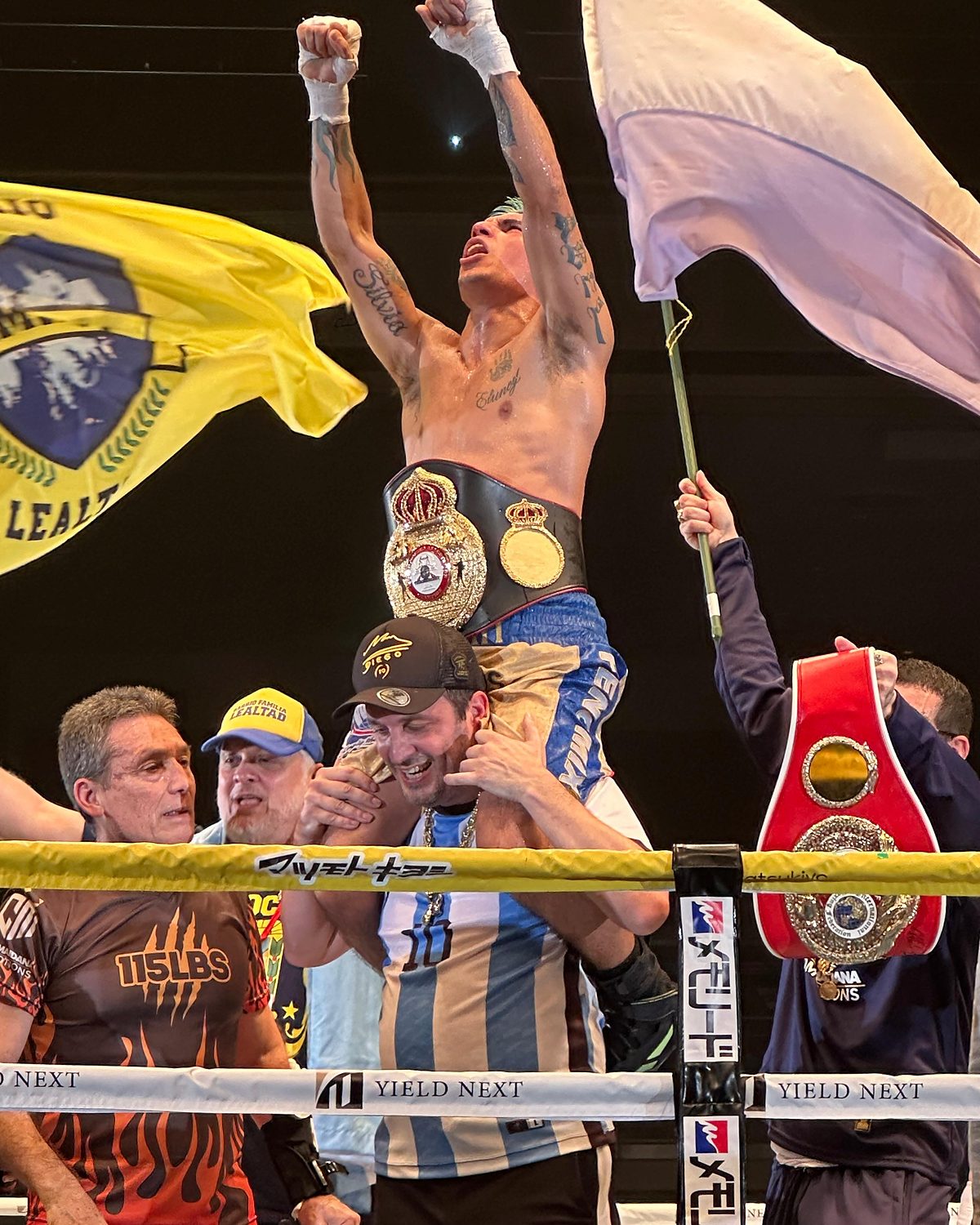Calabrese, con la camiseta argentina, carga en hombros a Fernando «Puma» Martínez sobre un ring en Japón; Martínez levanta los puños con el cinturón de la Asociación Mundial de Boxeo en la cintura, entre banderas