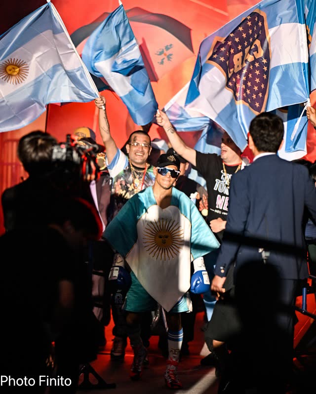 Fernando «Puma» Martínez camina hacia el ring en Japón envuelto en la bandera argentina, rodeado por su equipo con banderas celestes y blancas