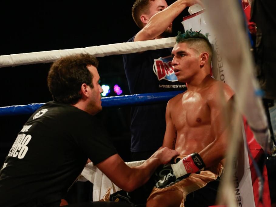 Calabrese, agachado en la esquina del ring, le habla a su boxeador sentado en el banquito entre round y round